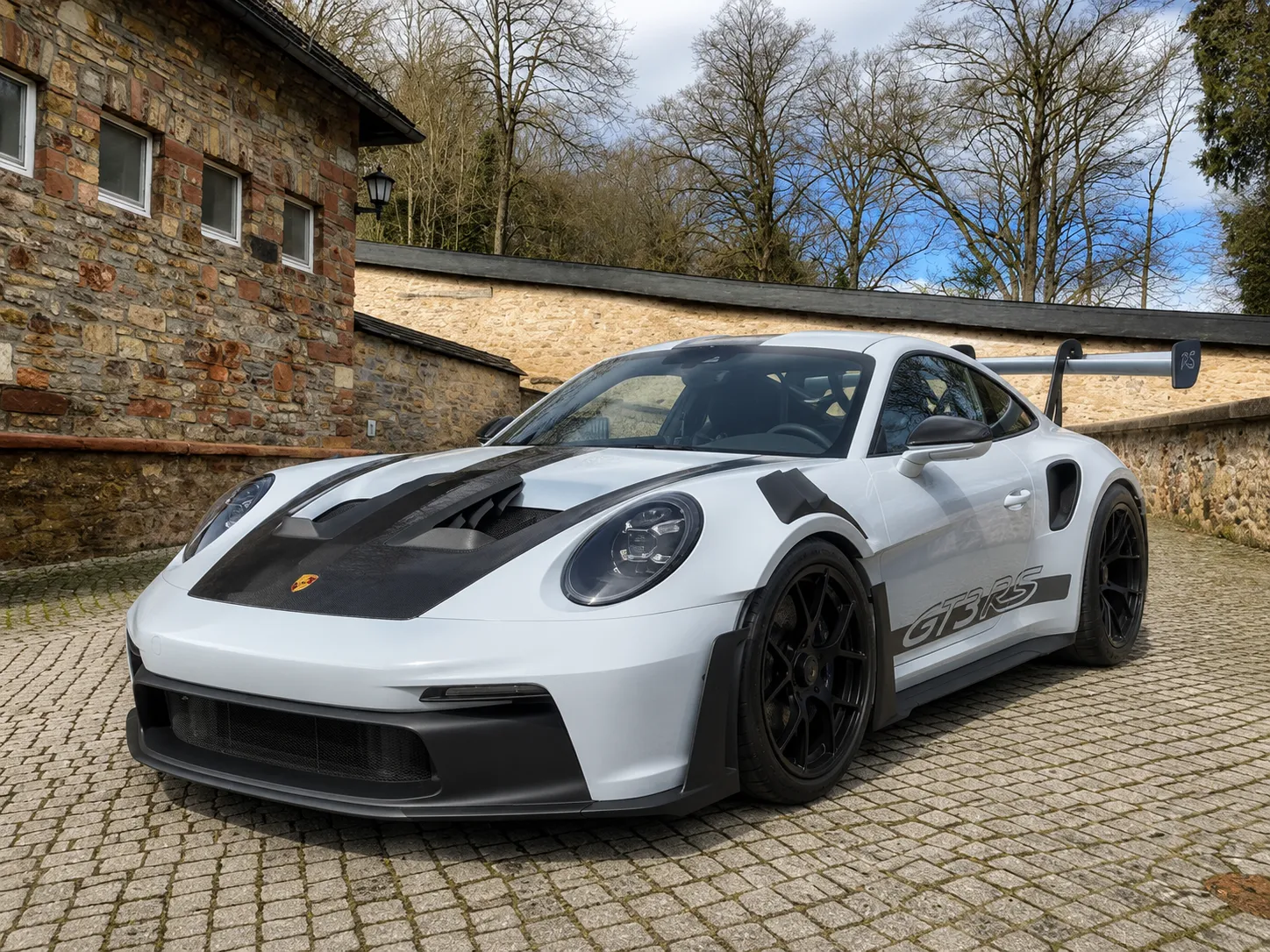 Zuletzt angekaufter Porsche 992 GT3 RS in Weiß vor einer Steinmauer